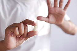 man holding pills with stop hand sign